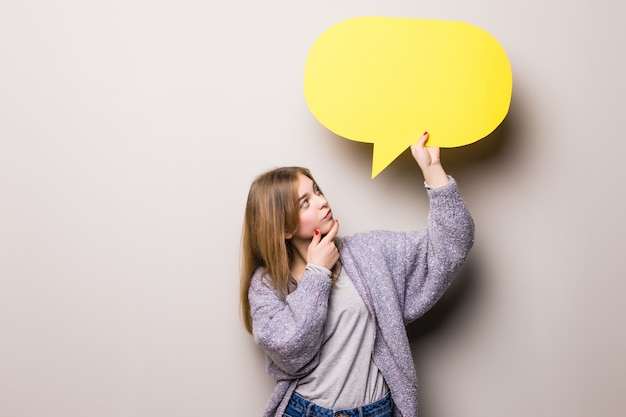 Young beautiful greaming girl holding a green bubble for text, isolated