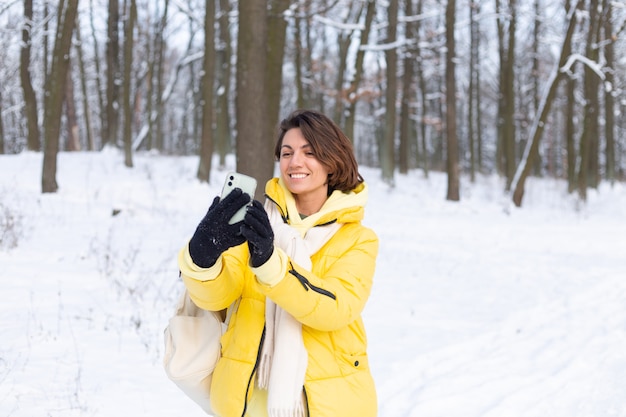 Young beautiful happy cheerful woman in the winter forest video blog, makes a selfie photo