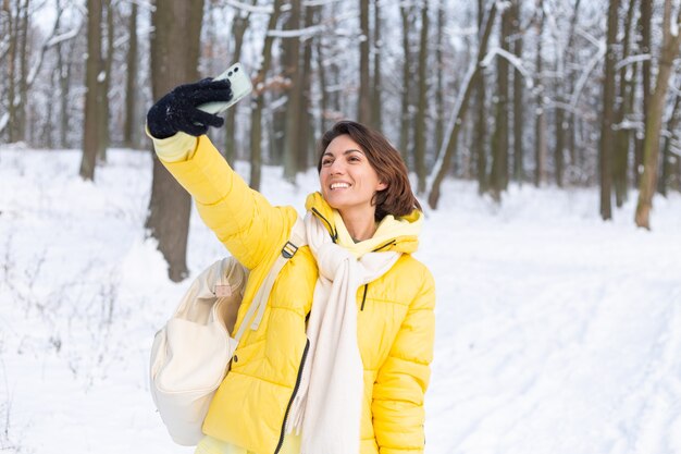 冬の森のビデオブログで若い美しい幸せな陽気な女性は、自分撮り写真を作ります