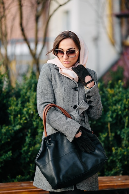 Young beautiful happy woman in a coat posing at the park