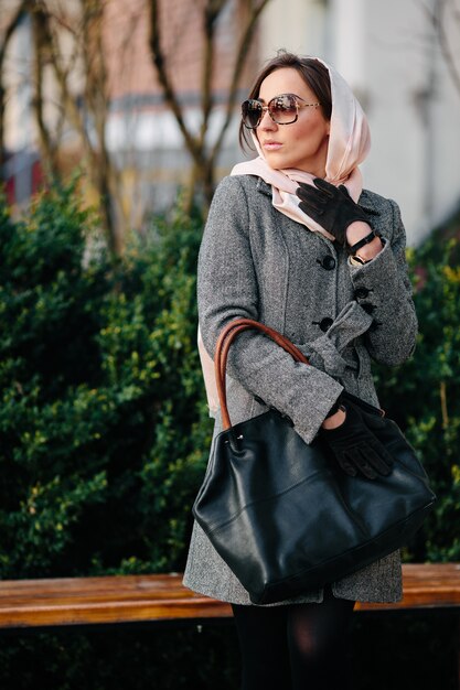 Young beautiful happy woman in a coat posing at the park