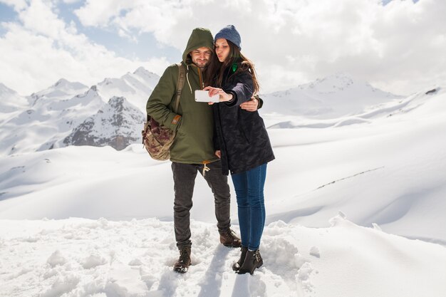 Young beautiful hipster couple hiking in mountains, winter vacation traveling, man woman in love