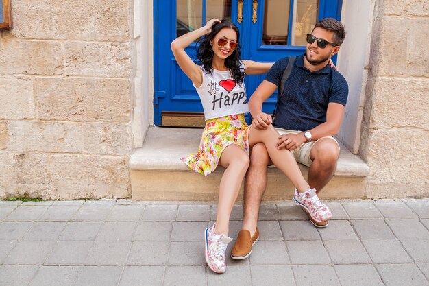 Young beautiful hipster couple in love sitting on old city street