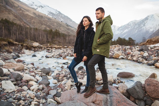 Young beautiful hipster couple in love, walking by the river, wild nature, winter vacation