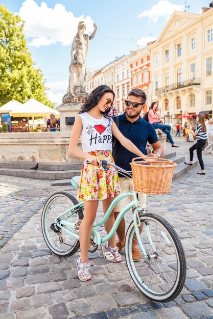 Young beautiful hipster couple in love walking with bicycle on old city street