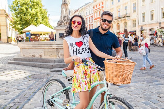 Young beautiful hipster couple in love walking with bicycle on old city street