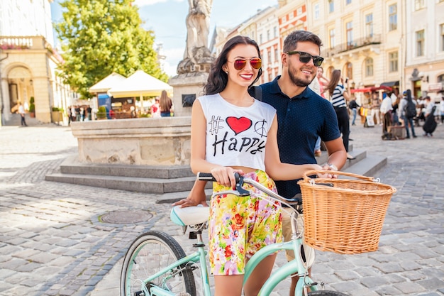 Молодая красивая хипстерская влюбленная пара гуляет с велосипедом по улице старого города