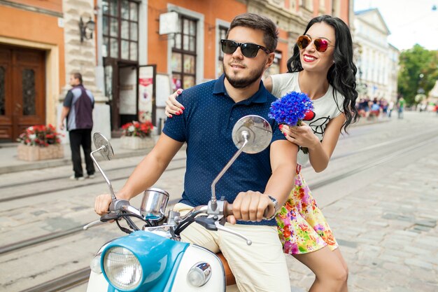 バイクの街の通りに乗って若い美しい流行に敏感なカップル