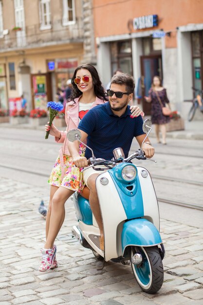 バイクの街の通りに乗って若い美しい流行に敏感なカップル