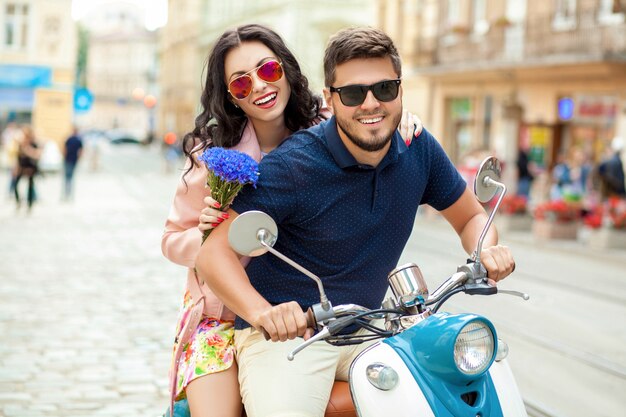 Young beautiful hipster couple riding on motorbike city street