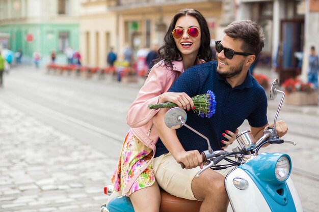 バイクの街の通りに乗って若い美しい流行に敏感なカップル