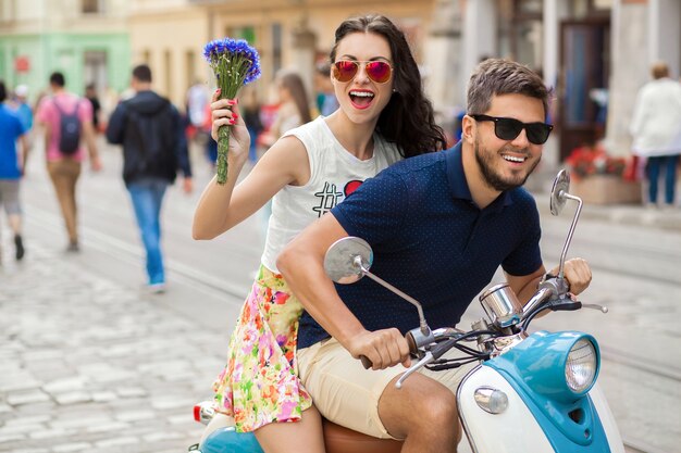 バイクの街の通りに乗って若い美しい流行に敏感なカップル