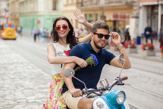 バイクの街の通りに乗って若い美しい流行に敏感なカップル