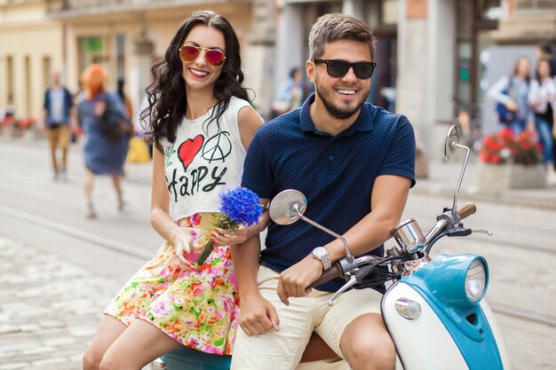 バイクの街の通りに乗って若い美しい流行に敏感なカップル