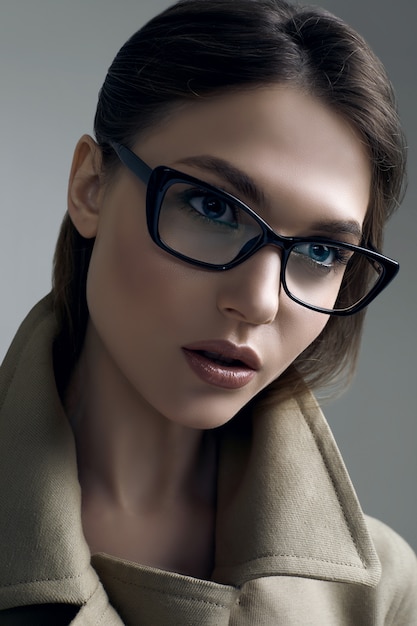 Young beautiful hipster woman in fashionable coat and glasses