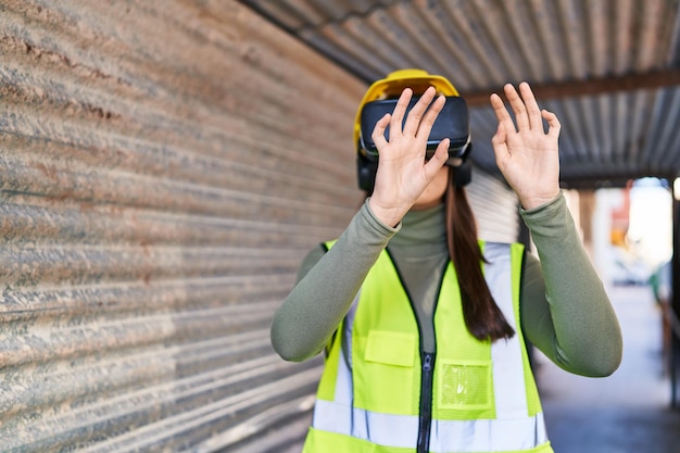 Architetto di giovane bella donna ispanica utilizzando occhiali per realtà virtuale in strada