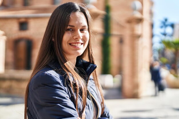 Foto gratuita giovane bella donna ispanica sorridente fiduciosa in piedi in strada