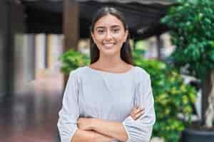 Free photo young beautiful hispanic woman standing with arms crossed gesture at street