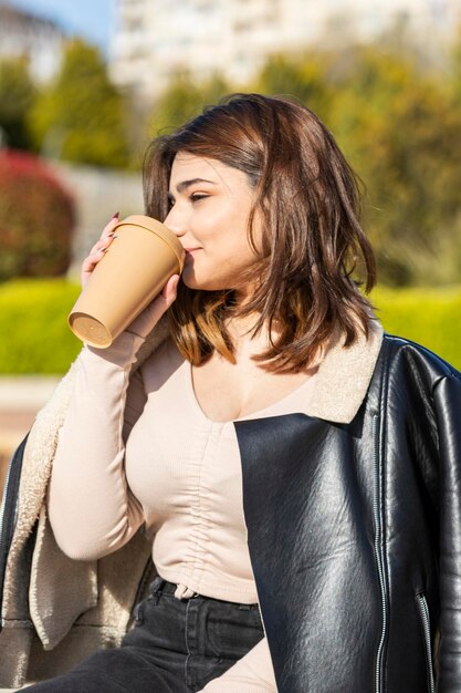 公園でコーヒーを飲む若い美しい女性高品質の写真