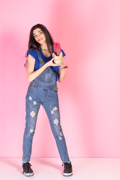 Young beautiful lady holding pink Cactus and standing on pink background High quality photo