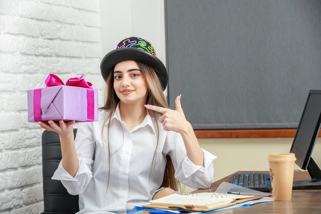 Young beautiful lady holding present box and point finer at it