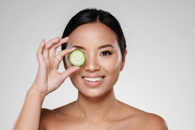 Young beautiful lady holding slices of cucumber