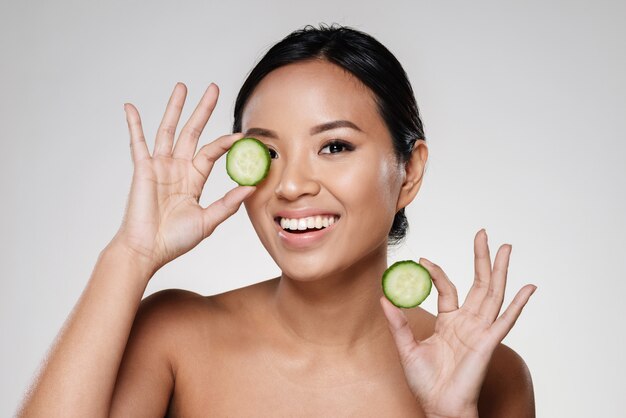 Young beautiful lady holding slices of cucumber