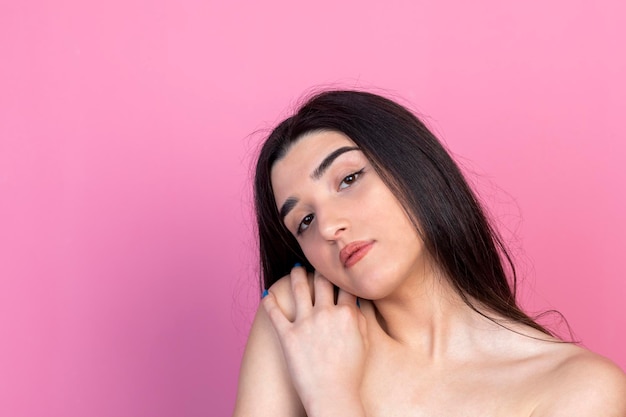 Young beautiful lady standing on pink background and looking at the camera