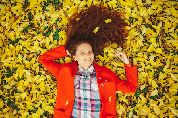 Young beautiful lady surrounded autumn leaves