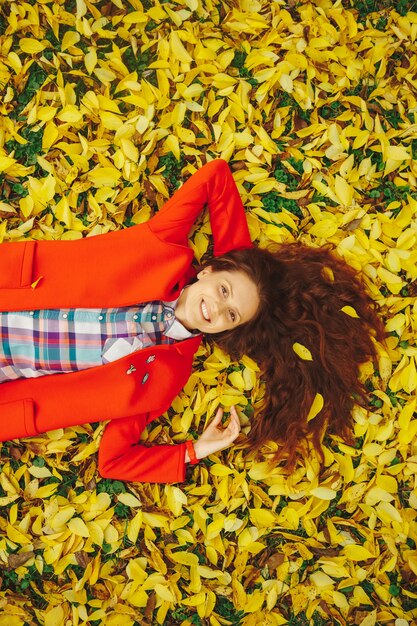Young beautiful lady surrounded autumn leaves