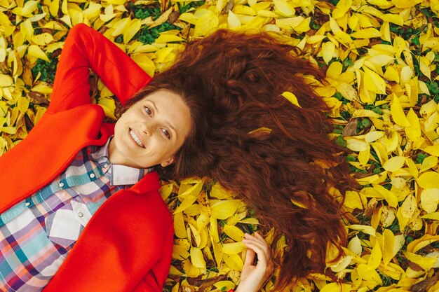 Young beautiful lady surrounded autumn leaves