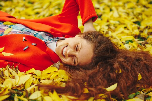 Young beautiful lady surrounded autumn leaves