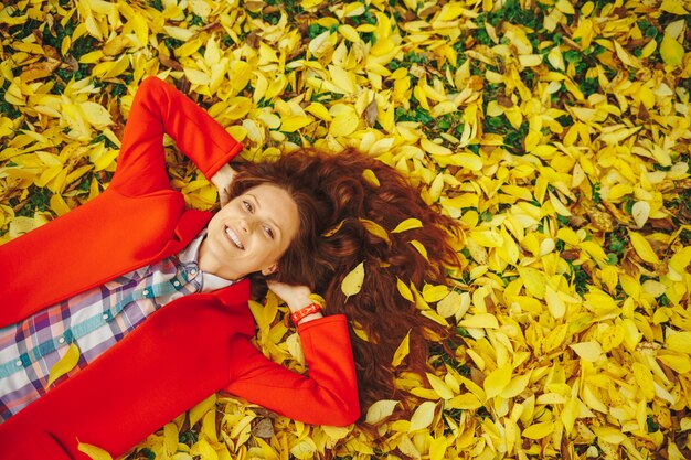 Young beautiful lady surrounded autumn leaves