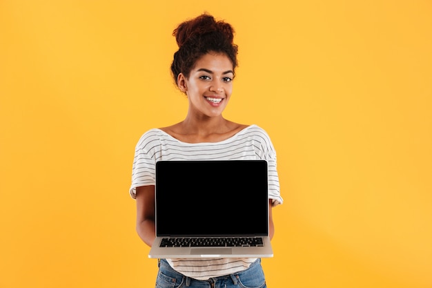 Young beautiful lady with curly hair showing laptop computer isolated