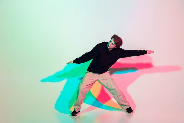 Young beautiful man dancing hip-hop, street style isolated on studio