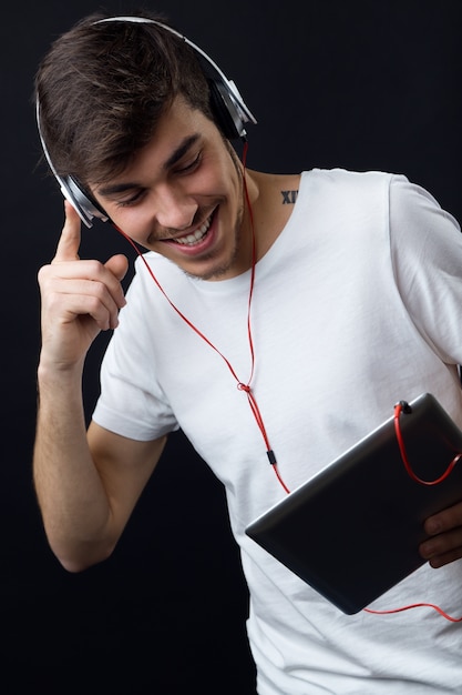 Young beautiful man listening to music. Isolated on black.