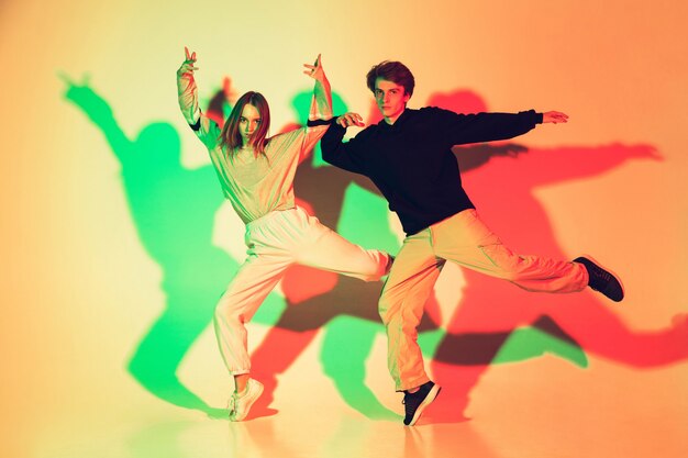 Young beautiful man and woman dancing hip-hop, street style isolated on studio