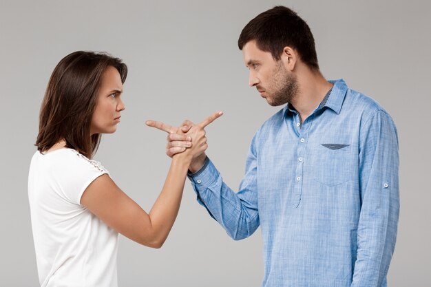 Young beautiful married couple posing over grey wall