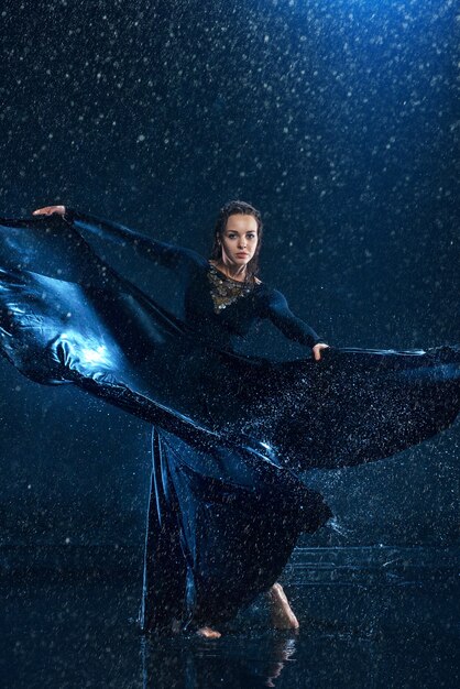 young beautiful modern dancer dancing under water drops