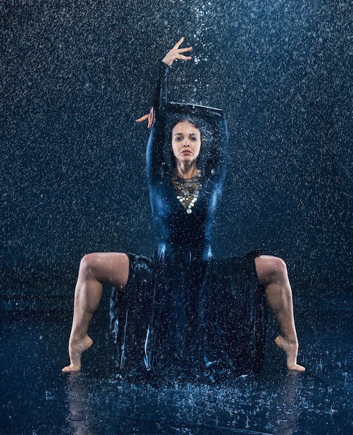 young beautiful modern dancer dancing under water drops