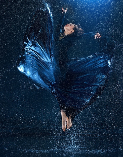 The young beautiful modern dancer dancing under water drops