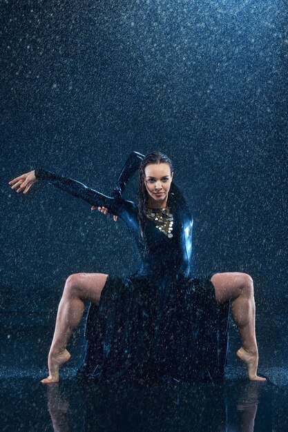 The young beautiful modern dancer dancing under water drops