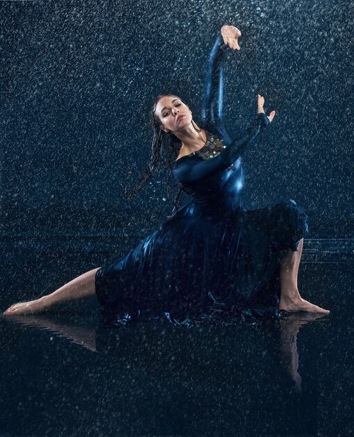 水滴の下で踊る若い美しいモダンダンサー