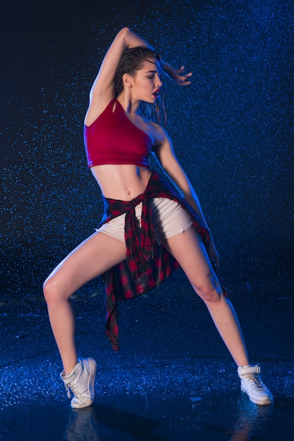 The young beautiful modern dancer dancing under water drops