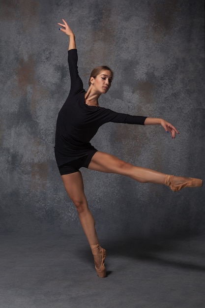 young beautiful modern style dancer posing on gray background