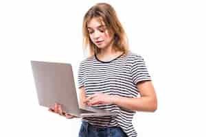 Free photo young beautiful modern woman having an laptop in hands, leaning on a white wall