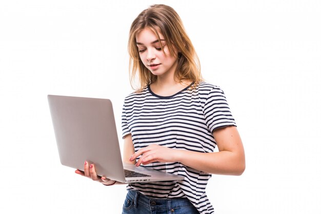 Young beautiful modern woman having an laptop in hands, leaning on a white wall