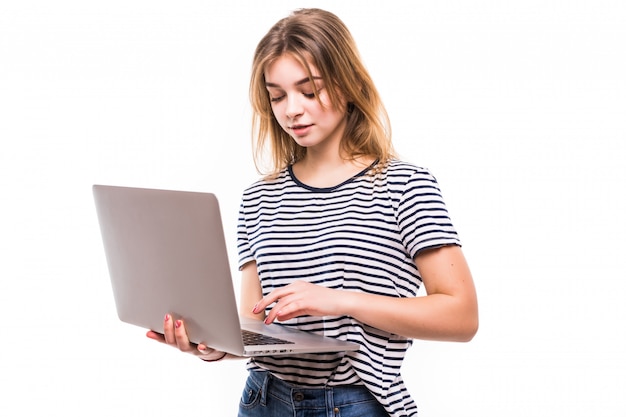 Young beautiful modern woman having an laptop in hands, leaning on a white wall