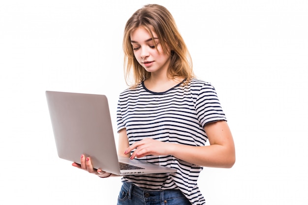 Молодая красивая современная женщина, имея ноутбук в руках, опираясь на белой стене
