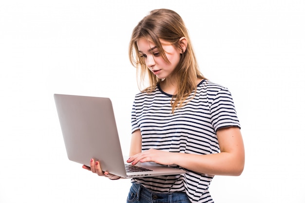 Young beautiful modern woman having an laptop in hands, leaning on a white wall